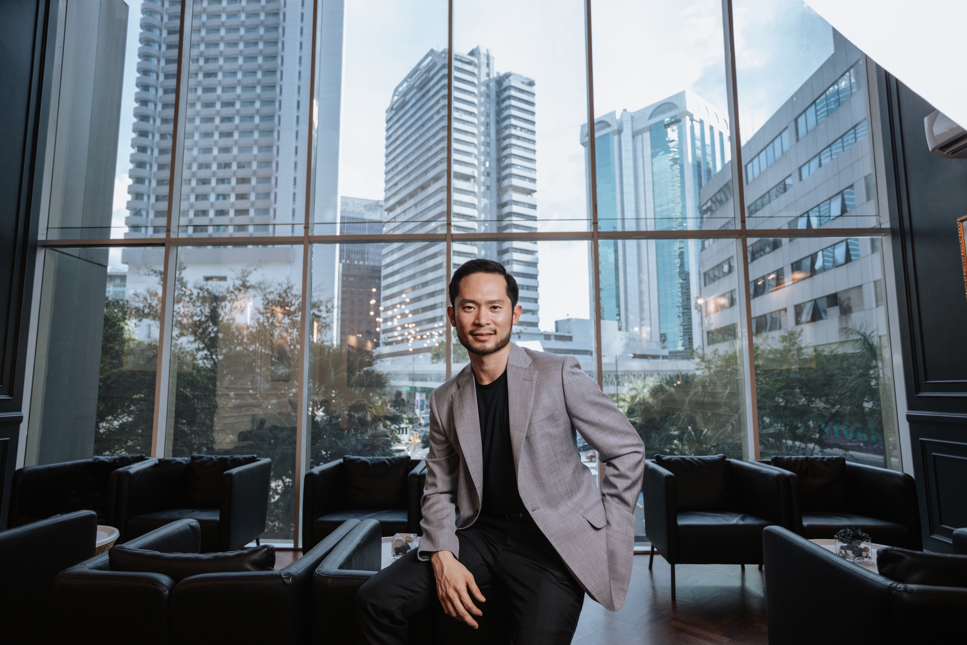 Chan Eu Boon seated confidently with Kuala Lumpur city skyline in the background.